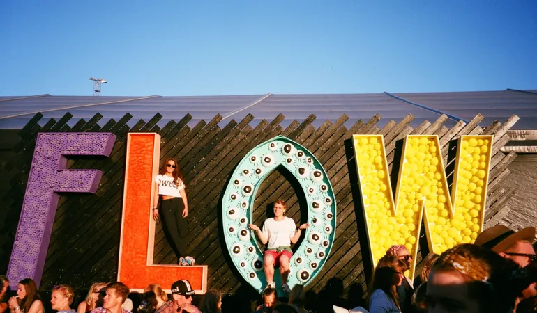 Flow spelled out in giant letters, with young people standing and sitting on it